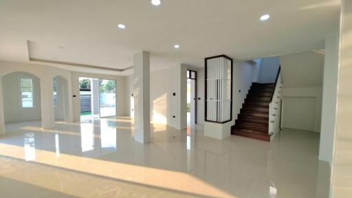 Spacious and modern living area with natural light, glossy floor tiles, and elegant staircase