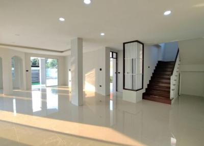 Spacious and modern living area with natural light, glossy floor tiles, and elegant staircase