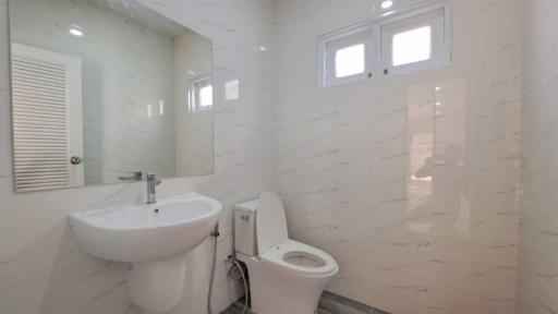 Modern white tiled bathroom with a sink, toilet, and shower