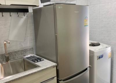 Compact modern kitchen with stainless steel appliances and white tiles