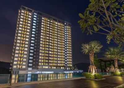High-rise residential building at night with illuminated windows and pool area