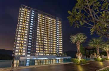 High-rise residential building at night with illuminated windows and pool area