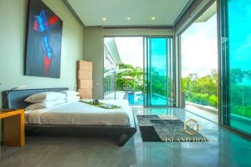 Spacious bedroom with large bed, floor-to-ceiling windows, and pool view