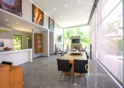 Modern and spacious living room with open plan kitchen, ample natural light, and sleek furniture
