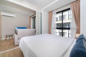 Modern bedroom interior with queen-sized bed, bright lighting, and balcony access