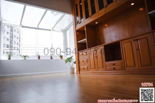 Spacious living room with high ceiling and wooden cabinetry