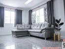 Spacious and modern living room interior with large windows, gray sectional sofa and glossy tiled floor