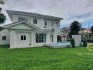 Elegant two-story house with a lush green lawn and a private pool