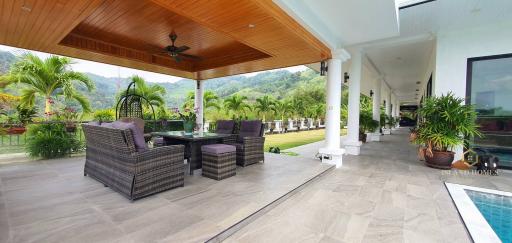 Spacious patio area with comfortable seating, ceiling fan, and a view of the garden and mountains