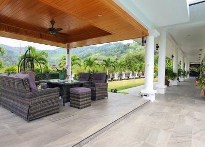 Spacious patio area with comfortable seating, ceiling fan, and a view of the garden and mountains
