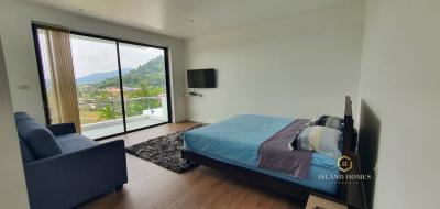 Cozy bedroom with a balcony view, furnished with a large bed, and modern amenities including a flat-screen TV