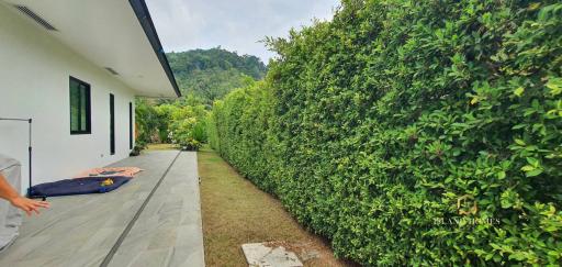 Spacious outdoor area with green hedge and mountain view