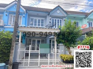 Blue two-story residential townhouse with a white fence, gate, and clear sky