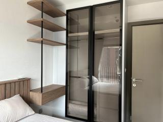 Modern bedroom with wooden shelves and sliding glass doors leading to a balcony