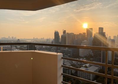 Sunset view from high-rise apartment balcony overlooking the city