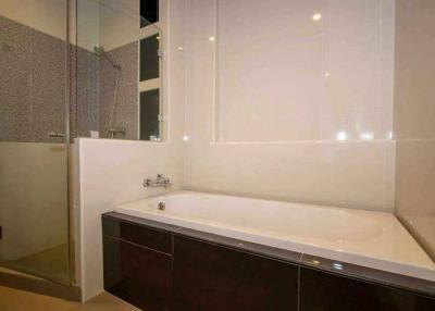 Modern bathroom interior with a clean bathtub, tiled walls, and glass shower partition