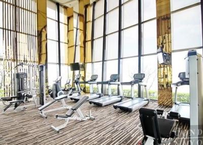 Modern gym in a residential building with large windows and a variety of equipment