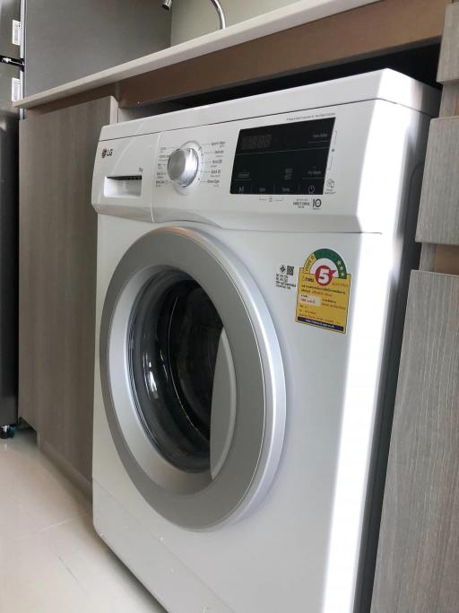 Modern white front-load washing machine in a clean laundry space