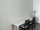 Minimalist dining area with a white table and black chairs