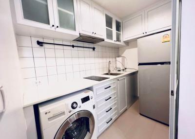 Compact modern kitchen with white cabinetry and built-in appliances