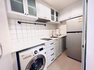 Compact modern kitchen with white cabinetry and built-in appliances