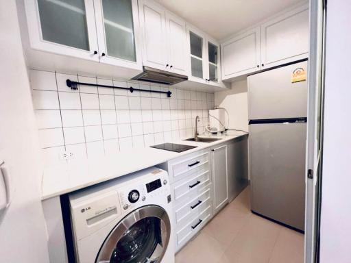 Compact modern kitchen with white cabinetry and built-in appliances