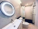 Modern bathroom with a glass shower enclosure, circular mirror, and gray tiles