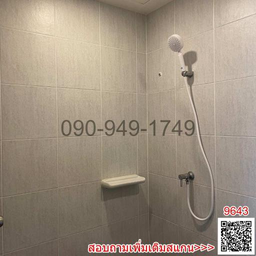 Modern tiled bathroom with wall-mounted shower head and built-in shelf