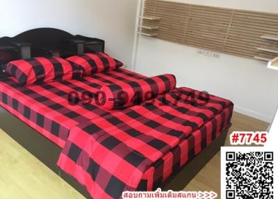 Modern bedroom with red and black checkered bedding and wooden flooring