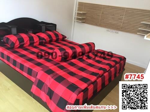 Modern bedroom with red and black checkered bedding and wooden flooring