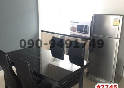 Modern kitchen with dining area featuring a glass table, black chairs, and stainless steel refrigerator