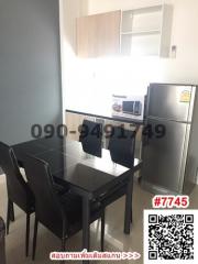 Modern kitchen with dining area featuring a glass table, black chairs, and stainless steel refrigerator