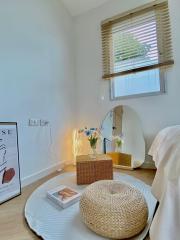 Cozy living room with natural light, a woven pouf, and a round table