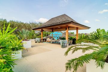 Spacious outdoor patio with wooden gazebo and tropical plants