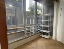 Interior view of a building's empty room with large windows and wooden flooring