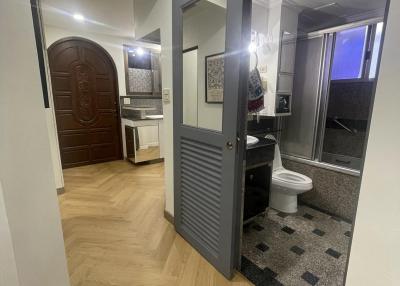 Corridor leading to bathroom with wooden floor and decorative door