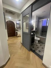 Corridor leading to bathroom with wooden floor and decorative door