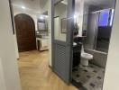 Corridor leading to bathroom with wooden floor and decorative door