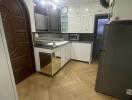 Modern kitchen with wooden flooring, white cabinets, and stainless steel appliances