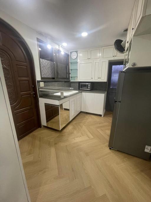 Modern kitchen with wooden flooring, white cabinets, and stainless steel appliances