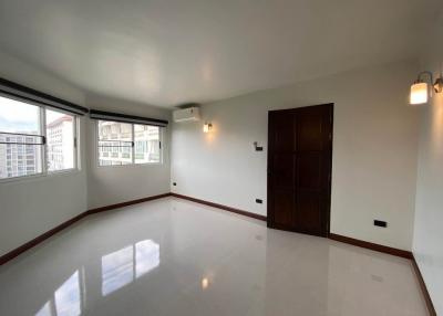 Spacious and well-lit living room with glossy tiled flooring and city view