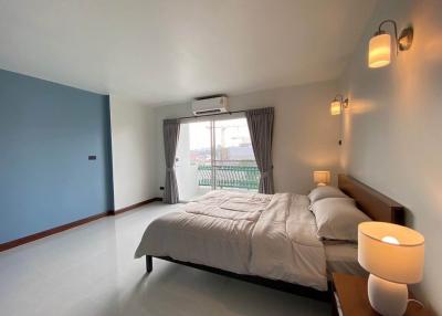 Spacious bedroom with queen-size bed, balcony access, and ample natural lighting
