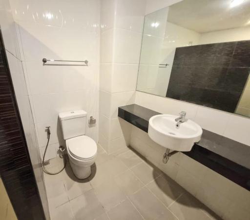 Modern clean bathroom with a wall-mounted sink, toilet, and bathtub