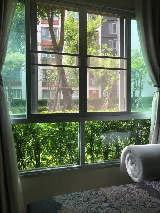 Bedroom with large window overlooking green outdoor area