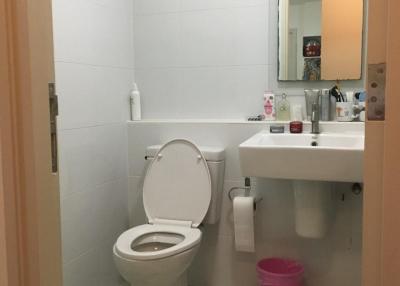 Compact white-tiled bathroom with toilet and sink