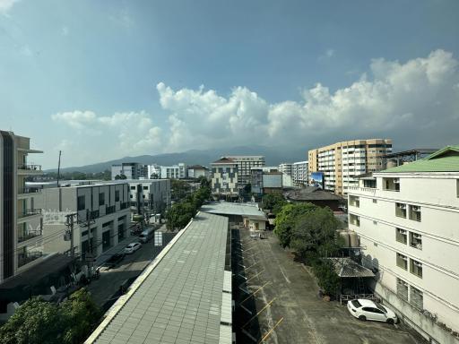 Urban landscape view from a building showing other buildings, street, and mountains in the distance