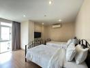Spacious bedroom with modern design, natural light, double beds, and amenities