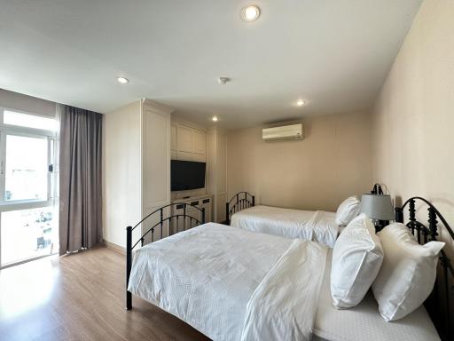 Spacious bedroom with modern design, natural light, double beds, and amenities