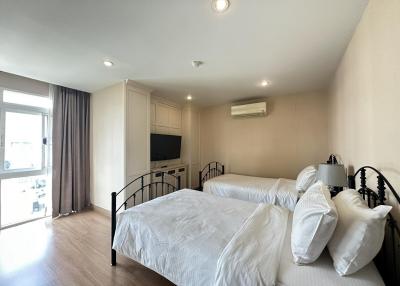 Spacious bedroom with modern design, natural light, double beds, and amenities
