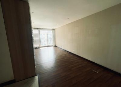 Spacious unfurnished living room with large window and hardwood flooring